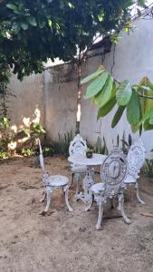 two white benches and a table and a chair at Moka Refúgium-Casa de praia aconchegante e espaçosa in Belém