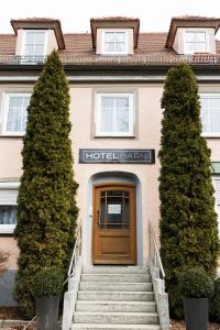 a building with a wooden door and two trees at Hotel Garni Promenade in Weißenhorn