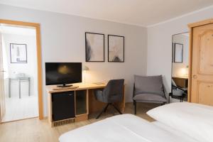 a bedroom with a desk with a television and two chairs at Hotel Garni Promenade in Weißenhorn