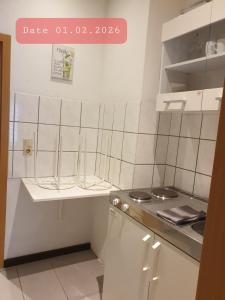 a kitchen with white tiled walls and white cabinets at FeWo Nina - Monteurwohnung in Weißenfels