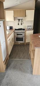 a kitchen with white cabinets and a stove top oven at KC Caravan Hire in Kinmel Bay