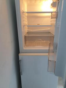 an empty refrigerator with its door open in a room at FeWo Nina 2 - Monteurwohnung in Weißenfels