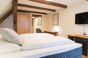 a bedroom with two beds and a flat screen tv at Hotel Garni Promenade in Weißenhorn