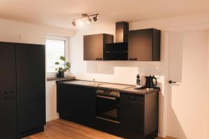 a kitchen with black cabinets and a black stove top oven at Appartment 1 Frau Isi in Mellrichstadt