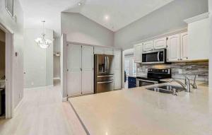 a kitchen with white cabinets and a stainless steel refrigerator at Florida house, 4br 2bt with private pool oasis in Naples