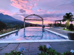 a swimming pool with a sunset in the background at Sembalun agro villa&restoran in Sembalun Lawang