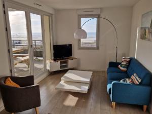 a living room with a blue couch and a tv at L'effet Mer de Stella in Stella-Plage