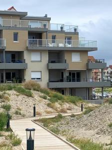 a building on the beach with a boardwalk at L'effet Mer de Stella in Stella-Plage