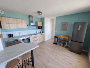 a large kitchen with blue walls and wooden floors at L'effet Mer de Stella in Stella-Plage +3 photos