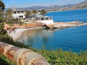 a view of a beach with palm trees and a building at varkiza luxury 2BD apartment in Varkiza