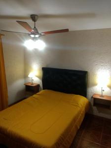 a bedroom with a yellow bed and two lamps at Tierra Nuestra in Villa Ciudad de América +7 photos
