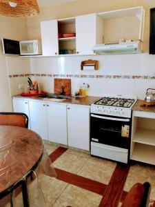 a kitchen with white cabinets and a stove and a table at Tierra Nuestra in Villa Ciudad de América