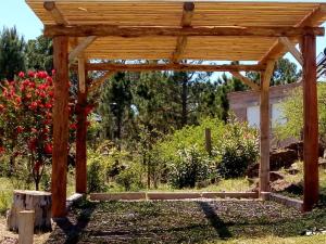 a wooden pergola in a garden with flowers at Tierra Nuestra in Villa Ciudad de América