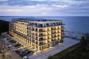 a building by the ocean with cars parked in front of it at Apartament 330 Przy Plaży, parking gratis! in Międzyzdroje