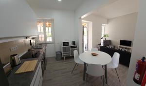 a kitchen with a white table and chairs in a room at Casa do Chafariz - Guest House in Cercal