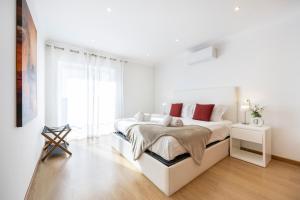 a white bedroom with a large bed with red pillows at Infinity Penthouse in Lagos +19 photos