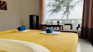 a bedroom with a yellow bed with blue towels on it at Vacation Beach in Hikkaduwa