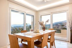 a dining room with a table and chairs and windows at Villa Bijoux SeaView Pool near Athens airport in Neos Voutzas