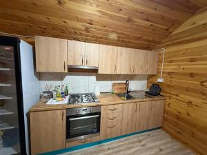 a kitchen with wooden cabinets and a stove at Bungaja Chalets in Shkodër +27 photos