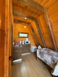 a kitchen in a log cabin with a bed in it at Bungaja Chalets in Shkodër