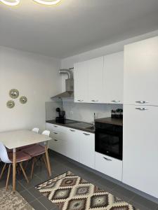 a kitchen with white cabinets and a table with chairs at Tale Sunset Apartment in Lezhë