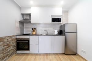 a kitchen with white cabinets and a stainless steel refrigerator at Modern Duplex Close to the Beach in Armação de Pêra +9 photos