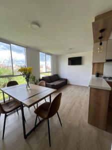 a kitchen and a living room with a table and chairs at Apartamento familiar de 3 habitaciones con parqueadero en Paipa in Paipa