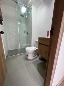 a bathroom with a toilet and a glass shower at Apartamento familiar de 3 habitaciones con parqueadero en Paipa in Paipa