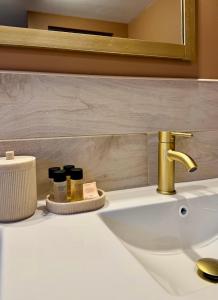 a bathroom sink with a gold faucet and cosmetics at Appartement à Ohain in Ohain