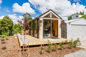 a small house with a wooden deck in a yard at Tiny on Access in Kerikeri