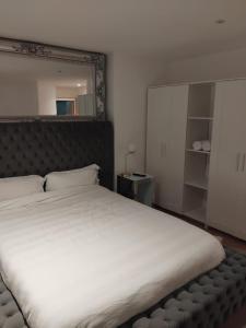 a bedroom with a large white bed with a large mirror at 2 Bedroom APARTMENT in Manchester