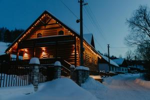 a log cabin with lights on in the snow at Granddrevenica in Malá Franková