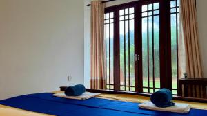 a bedroom with a bed with blue sheets and a window at Vacation Beach in Hikkaduwa