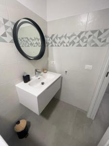a white bathroom with a sink and a mirror at Brezza Marina - Vacation Condo in Marina di Vasto