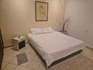 a small bedroom with a bed with white sheets at sharing is caring in Tamraght Ouzdar