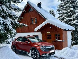 a red suv parked in front of a house at Horská chata Poustka in Benecko +70 photos