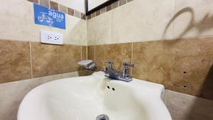 a bathroom with a white sink and a sign on the wall at Hotel estación Kristal - Corferias in Bogotá