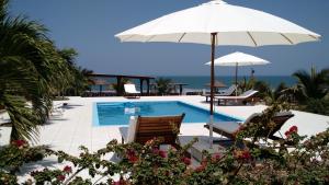 una piscina con sombrilla, sillas, mesa y sombrilla en Guille Bungalows, en Canoas de Punta Sal