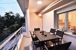 a balcony with a wooden table and chairs at Adams Suites in Paleo Tsifliki