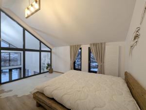 a bedroom with a large bed and large windows at Forest House Chalet Bran in Predeluţ