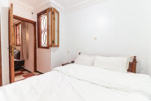 a white bedroom with two beds and a window at Appartement calme et ensoleillé avec WiFi haut débit in Sidi Ifni +11 photos