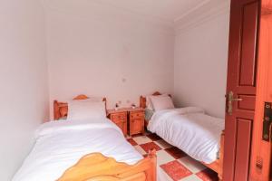 two beds in a small room with white walls at Appartement calme et ensoleillé avec WiFi haut débit in Sidi Ifni