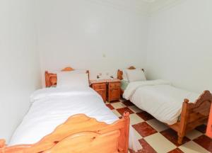 a bedroom with two beds and a tiled floor at Appartement calme et ensoleillé avec WiFi haut débit in Sidi Ifni