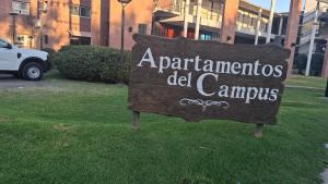 a sign in the grass in front of a building at Apartamentos del campus in Presidente Derqui