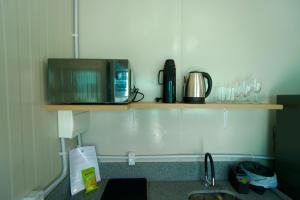 a kitchen with a microwave and a counter with a sink at Villammare Cachoeira in Florianópolis