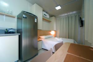 a small hotel room with a bed and a refrigerator at Villammare Cachoeira in Florianópolis