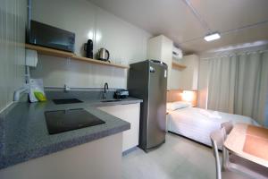 a kitchen with a refrigerator and a bed in a room at Villammare Cachoeira in Florianópolis