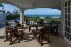 a patio with chairs and tables and a view of the ocean at Sandgate in Bridgetown