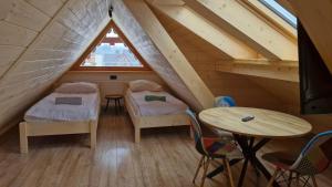 a room with two beds and a table in a attic at Chochołowsko-Witowski Wypoczynek in Witów