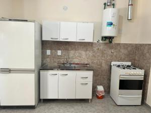 a kitchen with white cabinets and a sink and a stove at Cima Departamentos in Rivadavia +4 photos